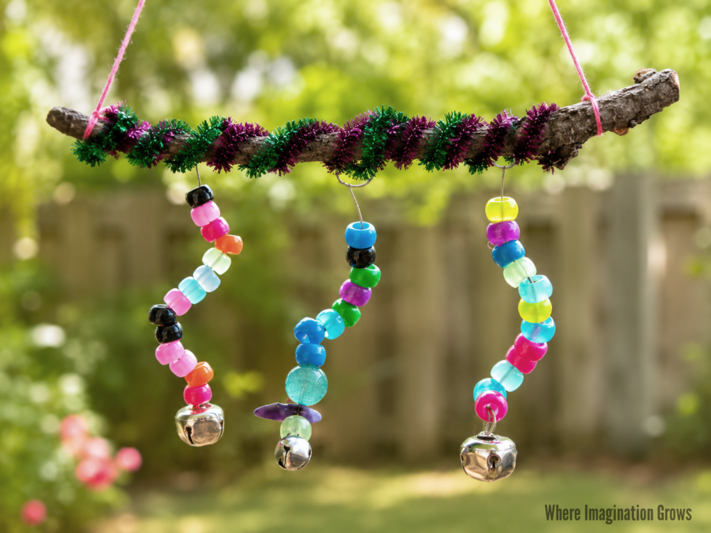 Colorful DIY stick wind chime made with pony beads, pipe cleaners, and bells